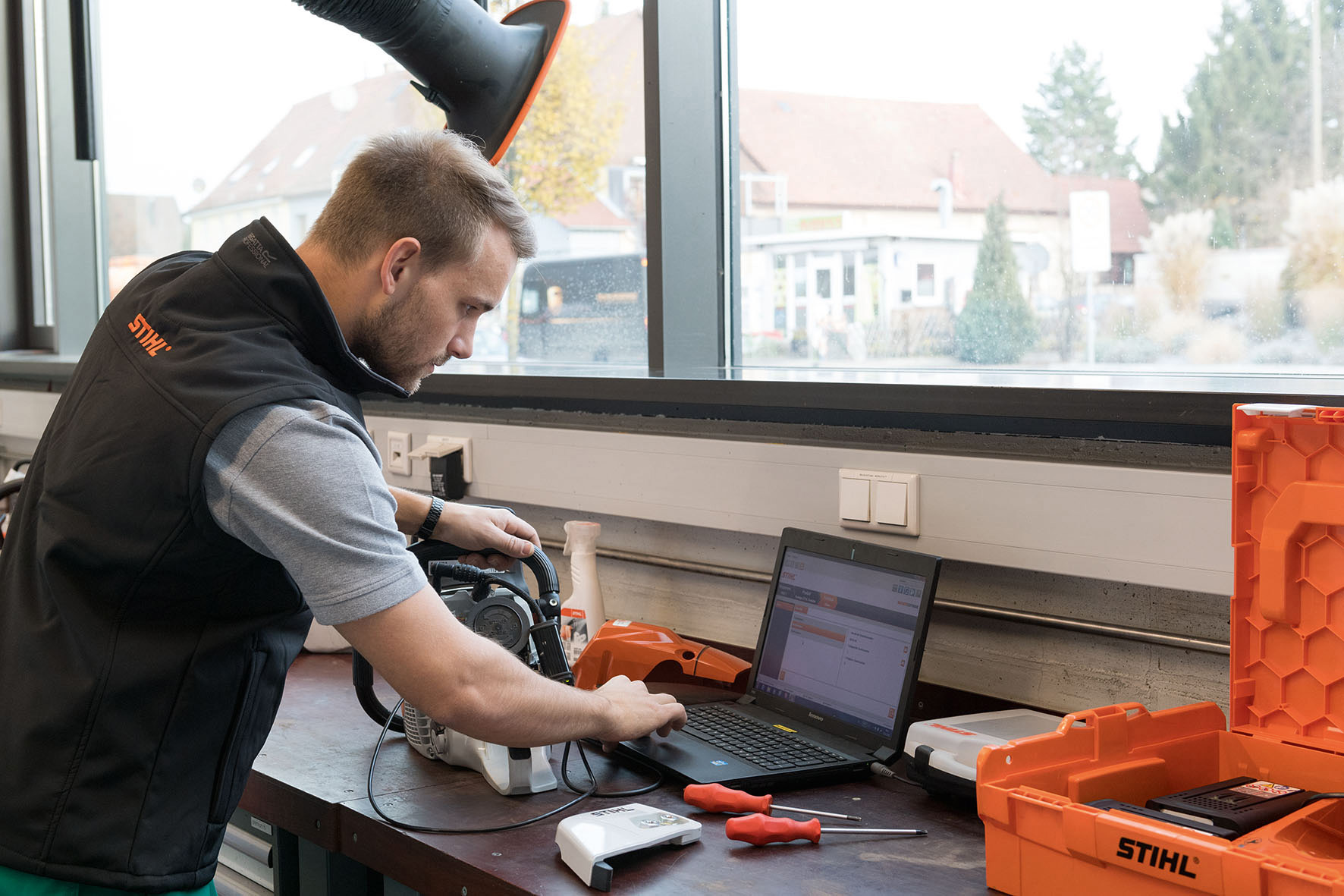 Man looking at a laptop in a workshop. Next to it a STIHL chainsaw.