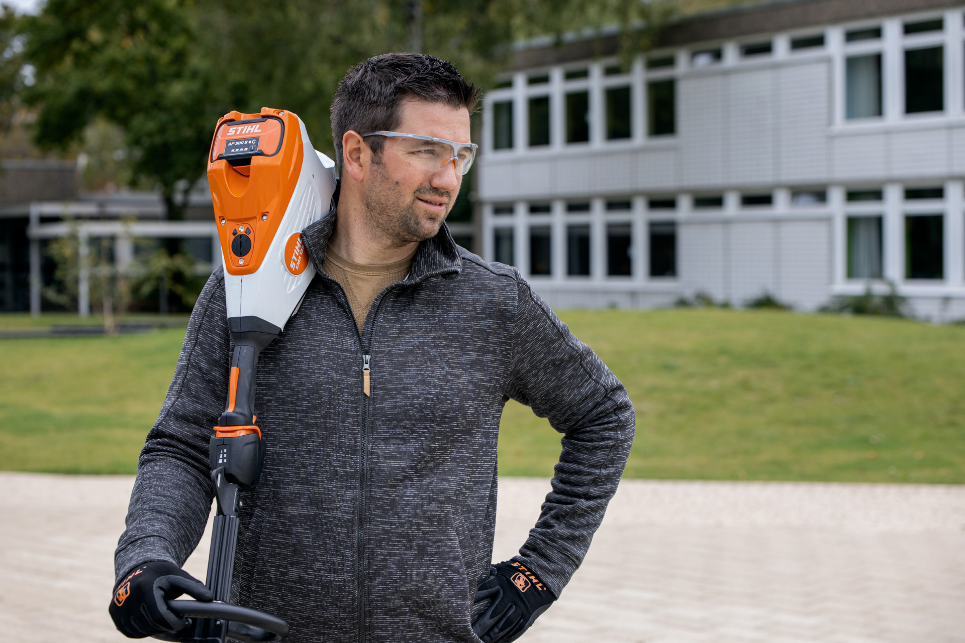 A man in front of a green area with a STIHL HSA 94 cordless hedge trimmer
