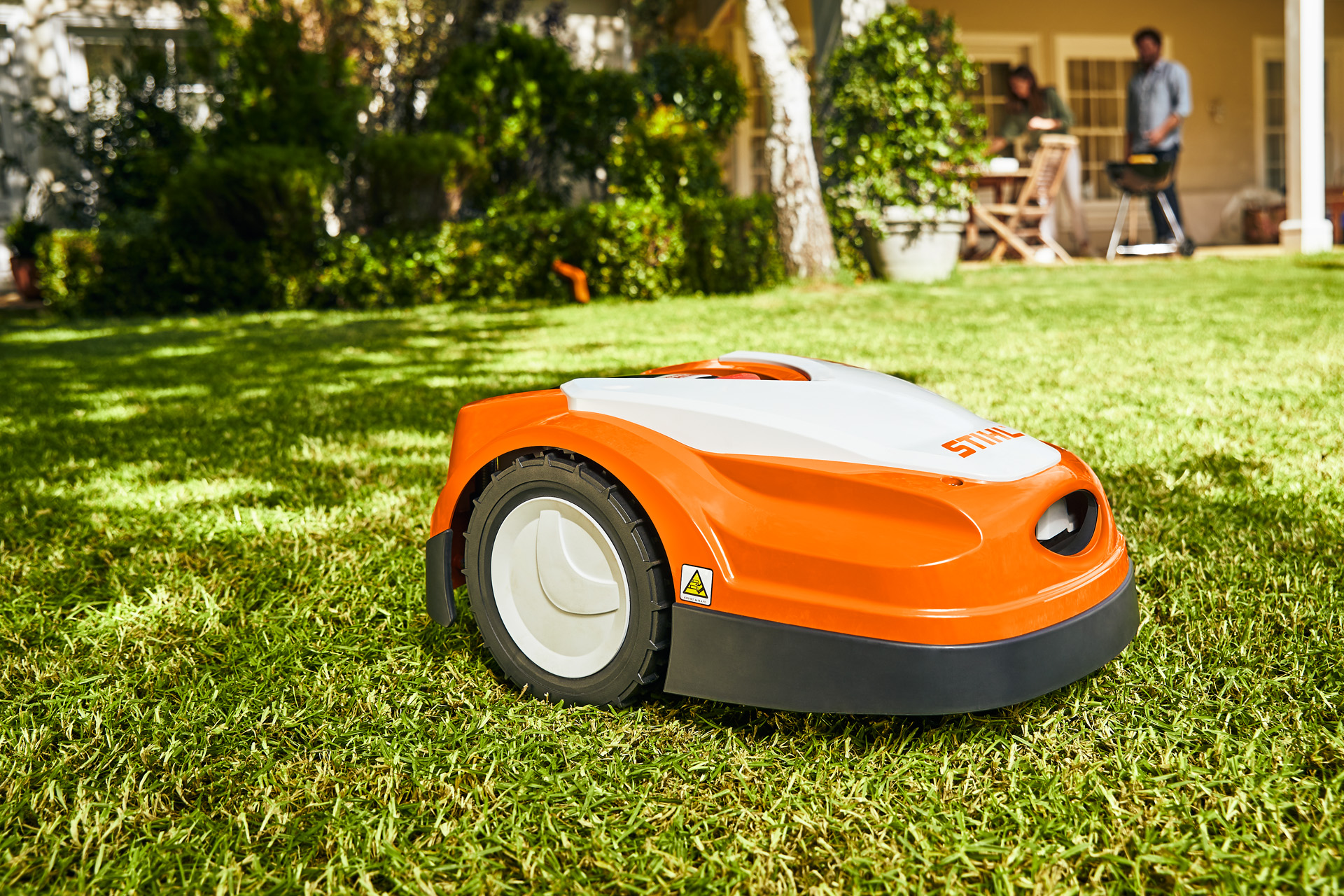 A STIHL iMOW® RI 422 robot lawn mower on a lawn in front of a house