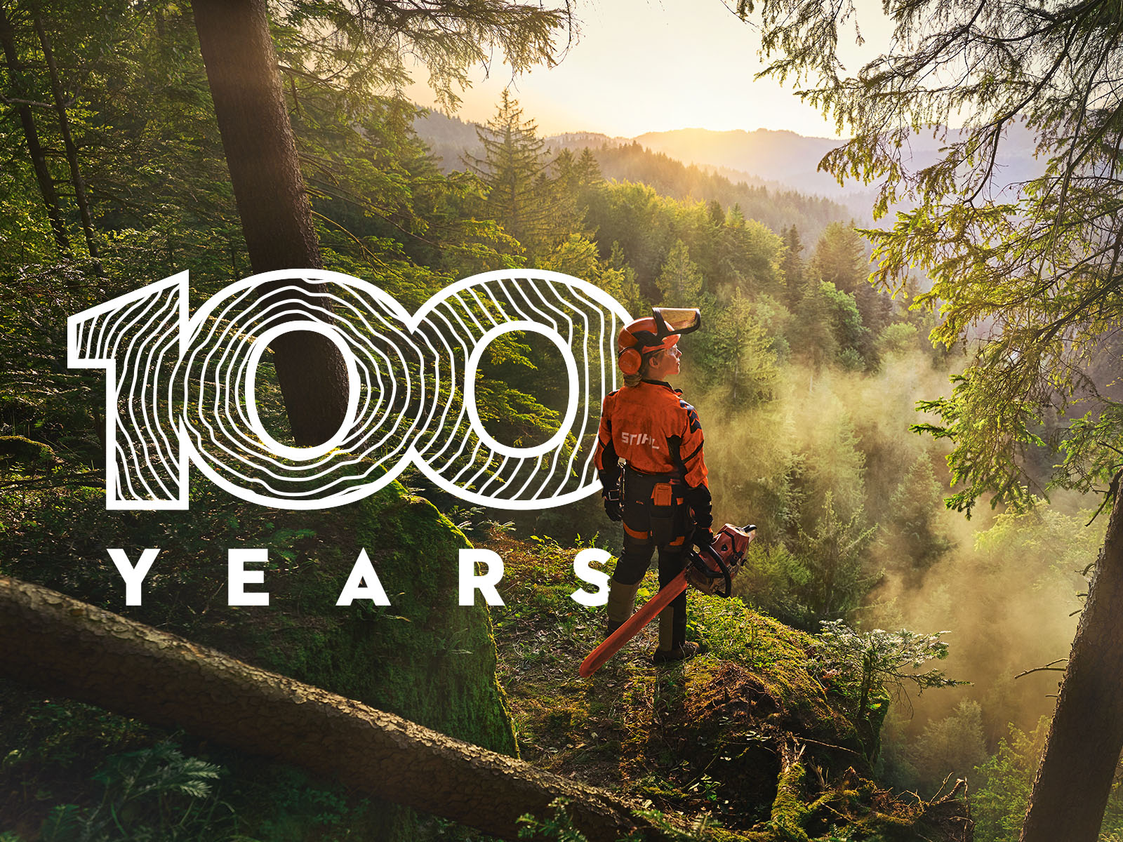 Person standing with chainsaw on hill in forest looking out at nature with text overlay reading 100 years