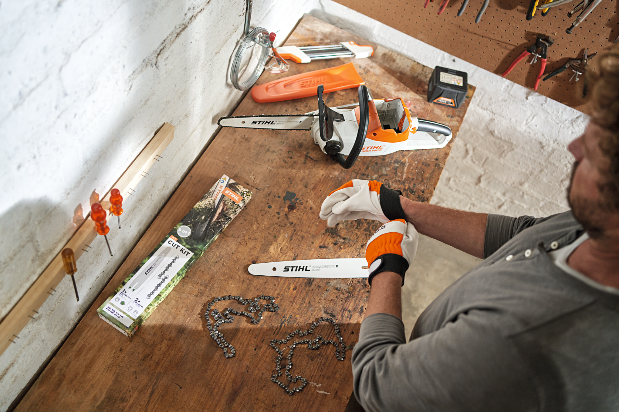 A man prepares the chainsaw for use with the help of  a maintenance kit.