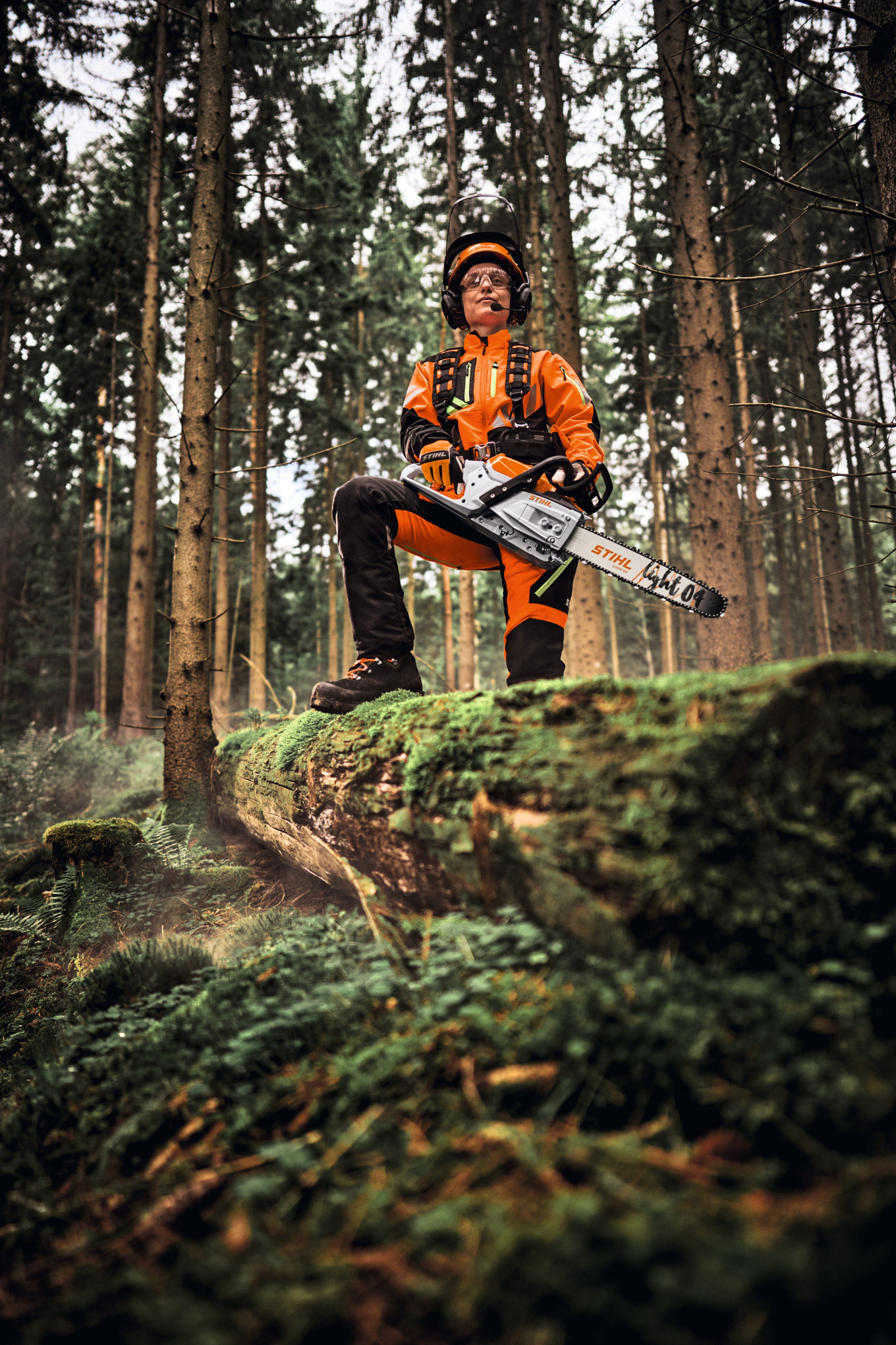 forestry worker with chainsaw one leg up on a log