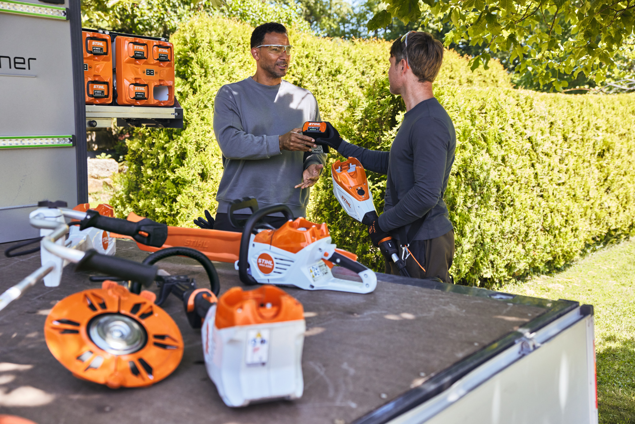 Two men inserting an AP 300 S into a battery hedge trimmer