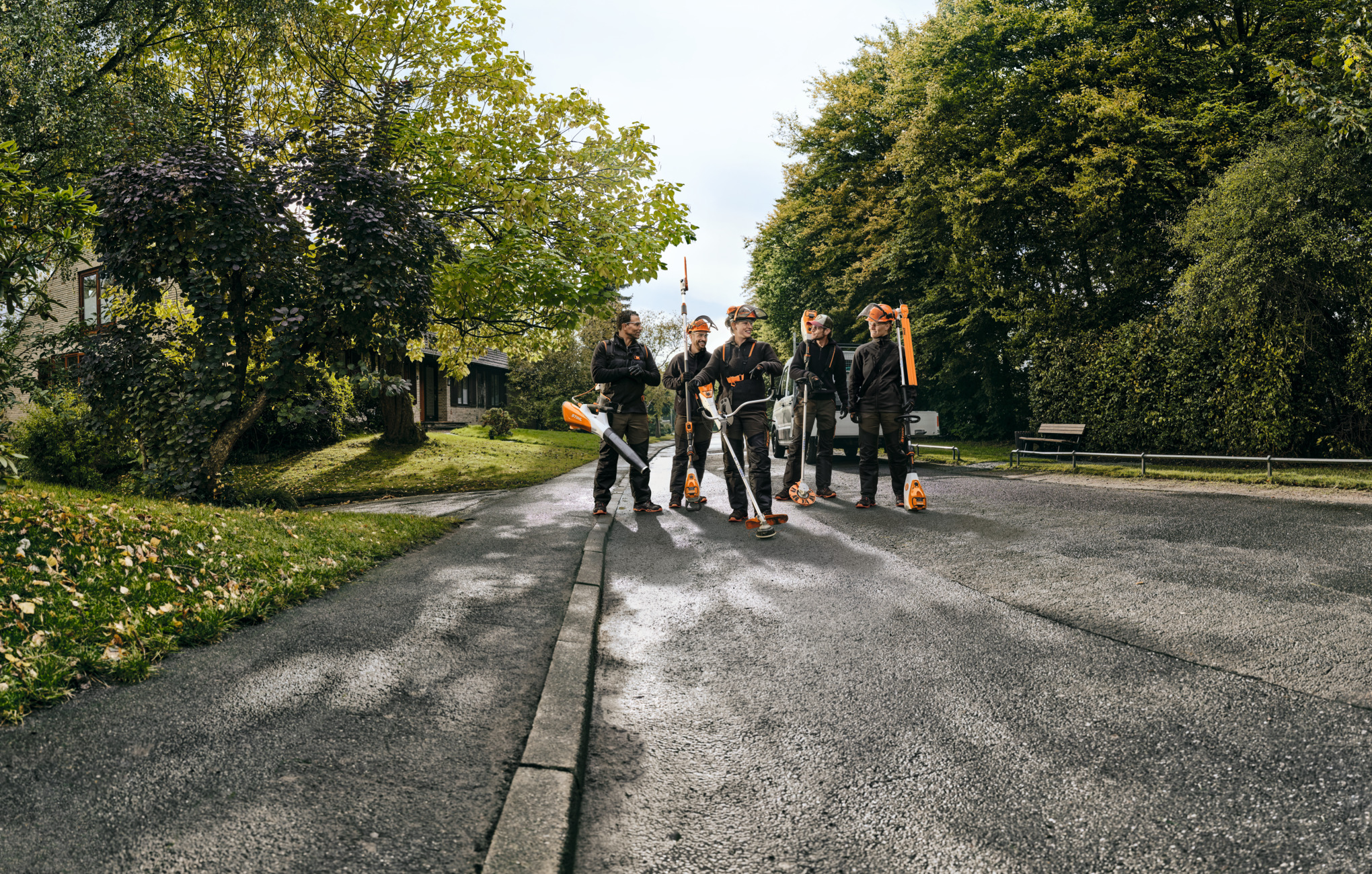 Five professionals working with STIHL cordless power tools walking down a road talking and laughing