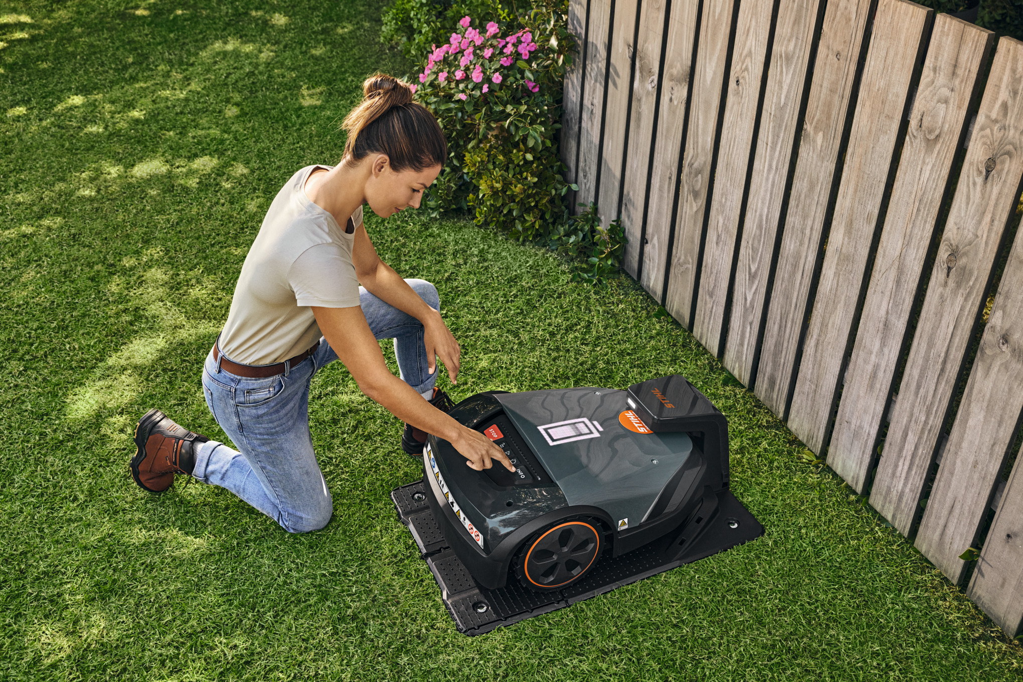 A STIHL iMOW® robot mower on decking with cable and operating instructions