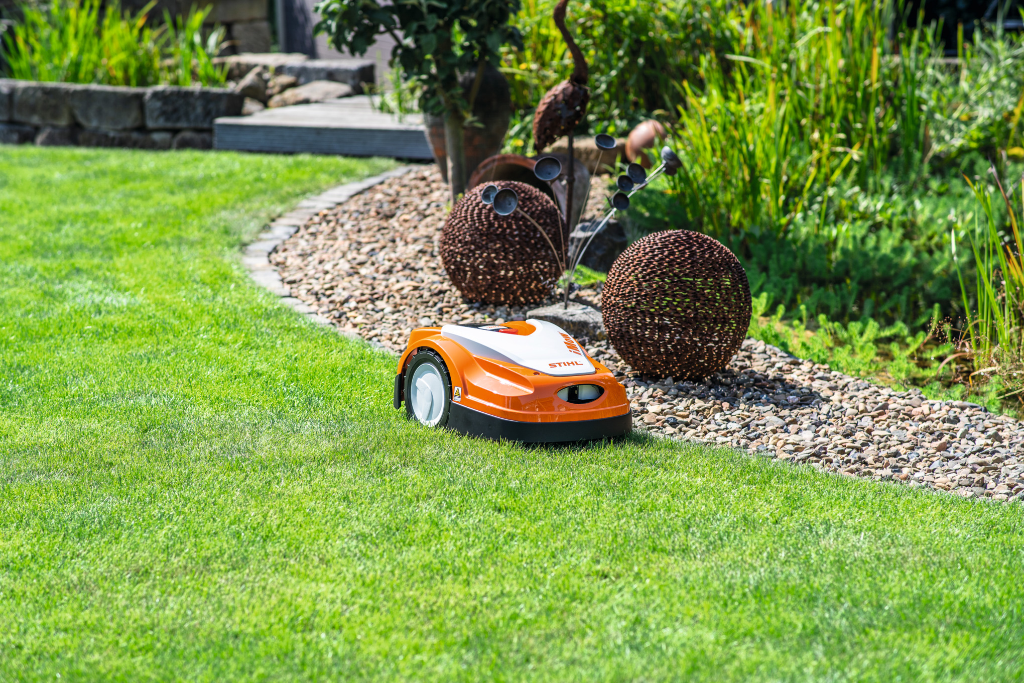 A STIHL iMOW® robot mower on a green lawn