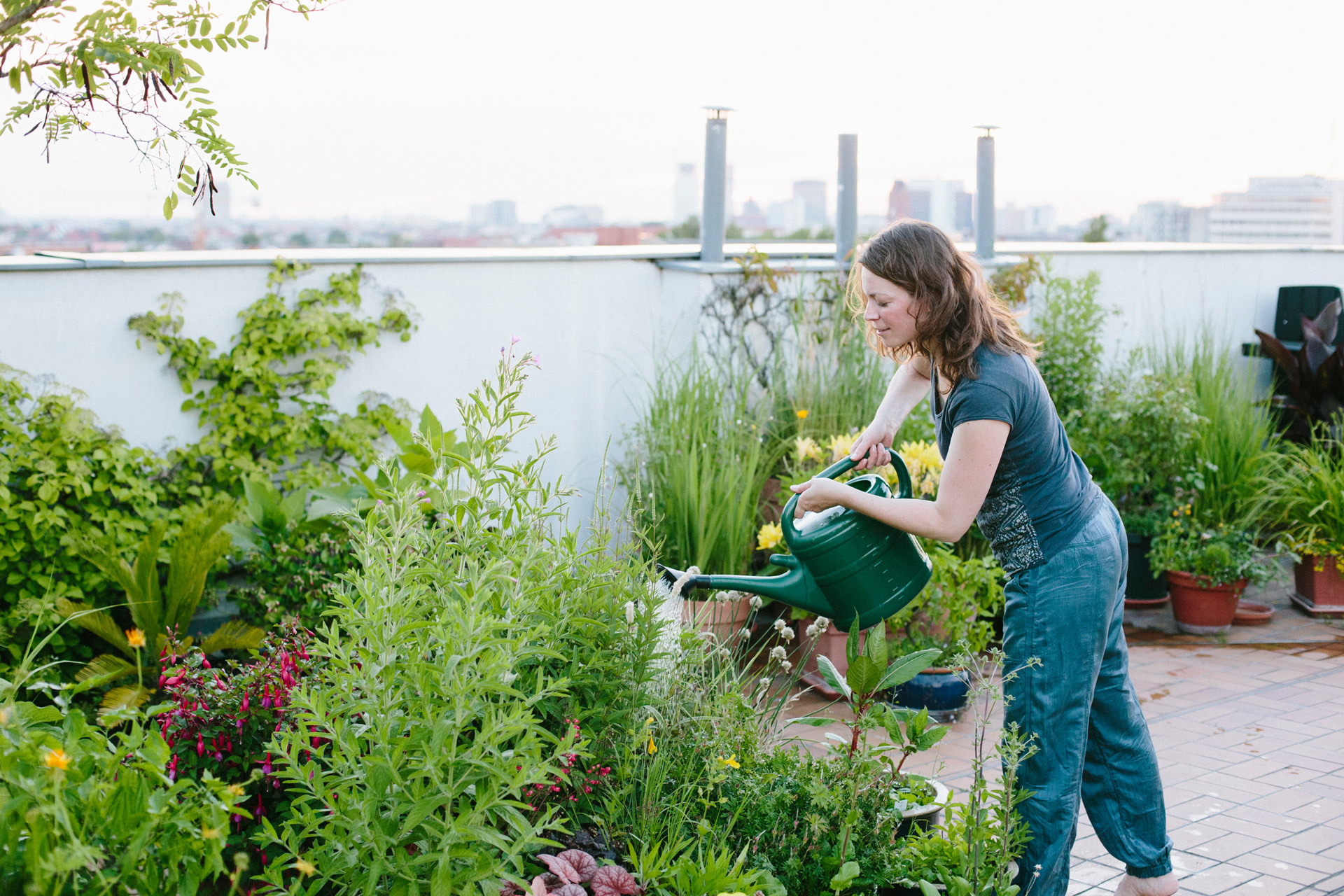 A woman watering plants on a roof terrace