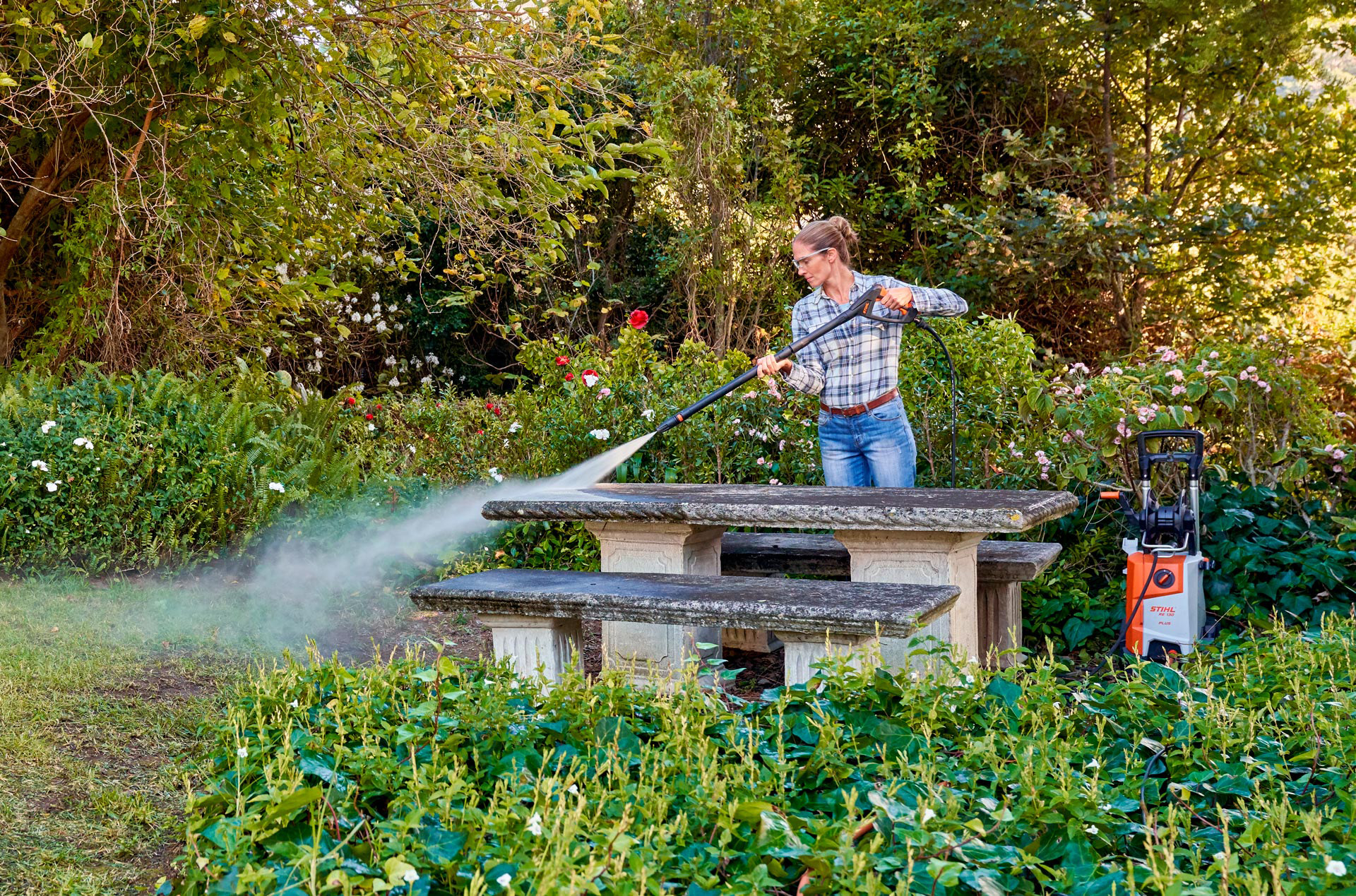 A woman cleaning her outdoor garden furniture with a STIHL high-pressure cleaner