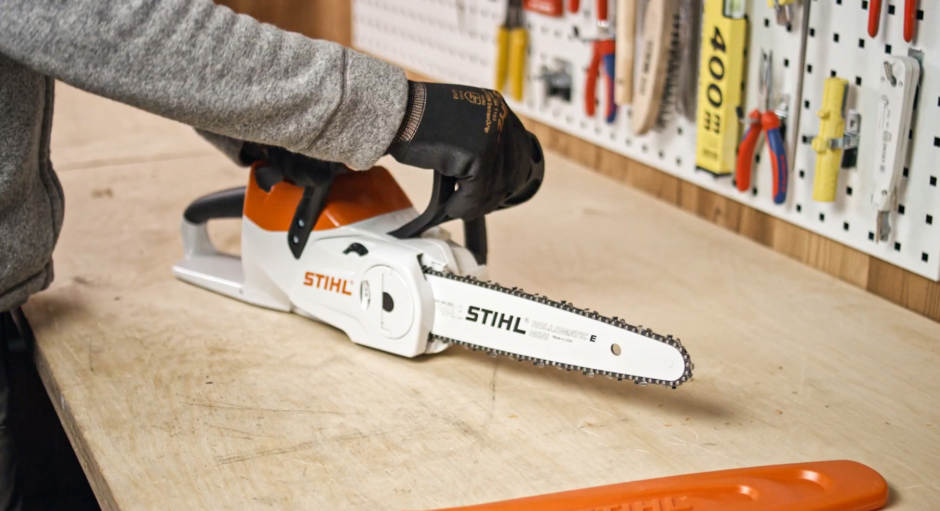 A STIHL MSA 120 cordless chainsaw on a workbench, with someone inspecting it