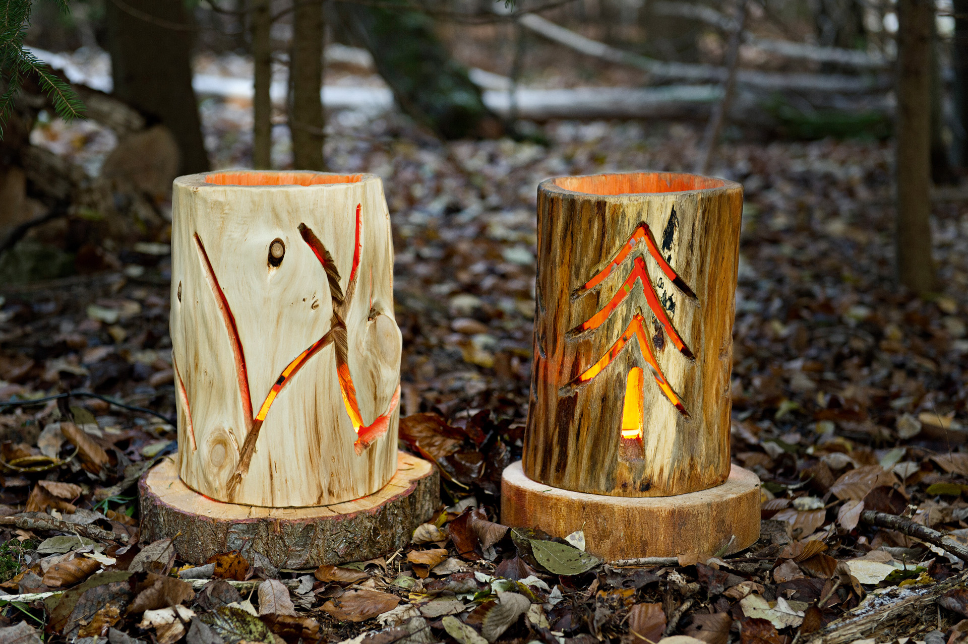 Two DIY log lanterns with patterns cut into the side and lights inside