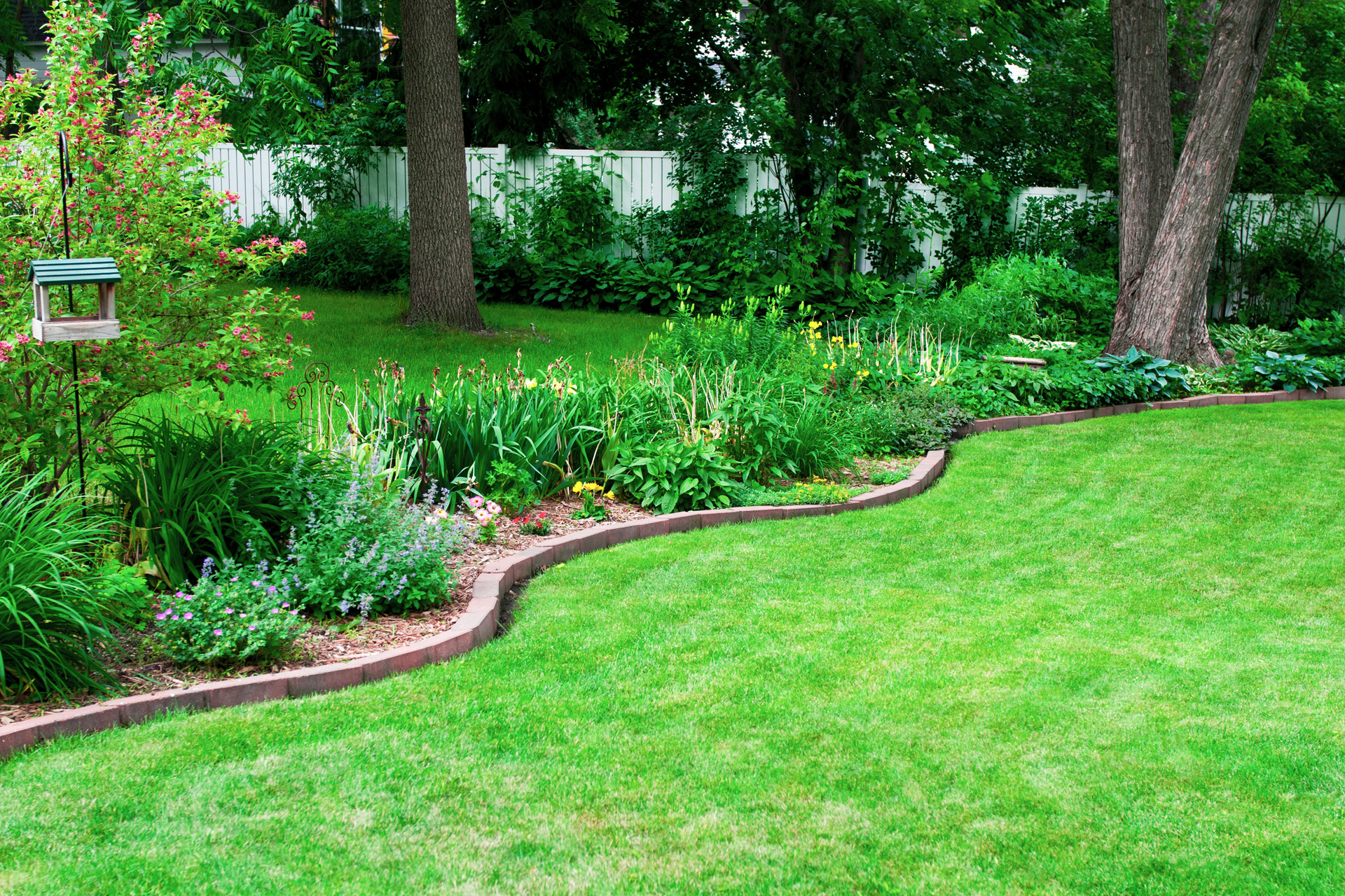 Garden bed with a DIY stone edging on a green lawn