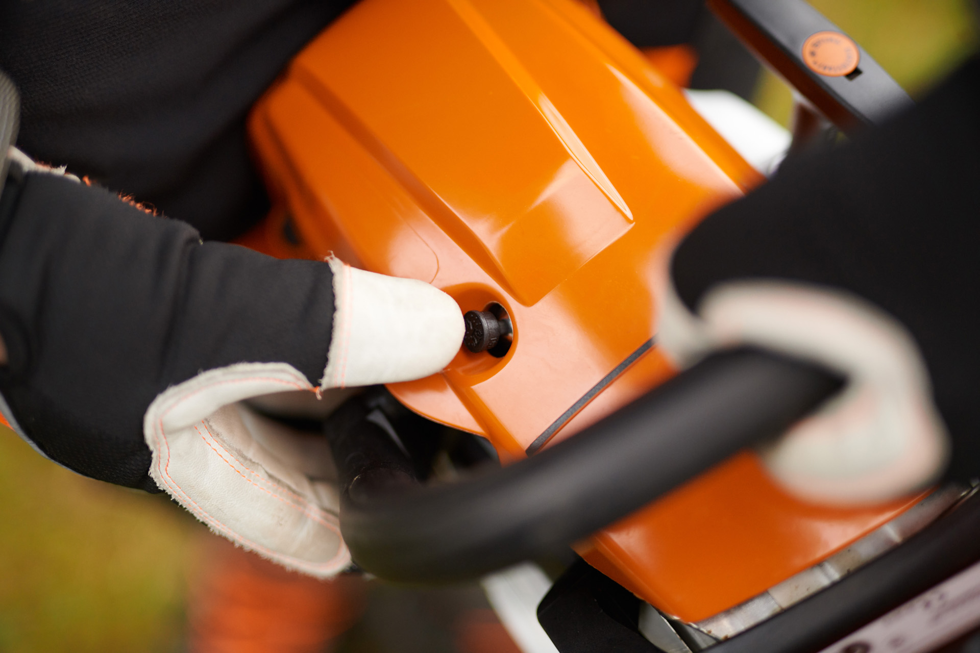 Close-up of a STIHL MS 261 C-M petrol chainsaw as someone wearing gloves actuates the decompression valve