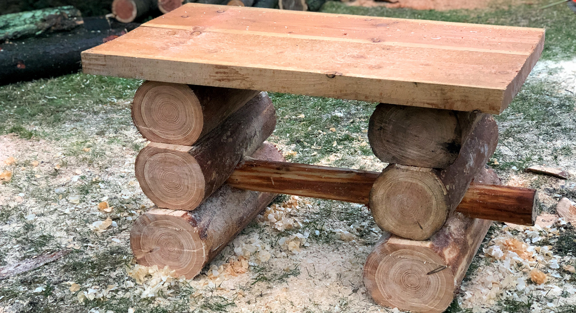 A finished wooden garden table on a lawn, surrounded by sawdust