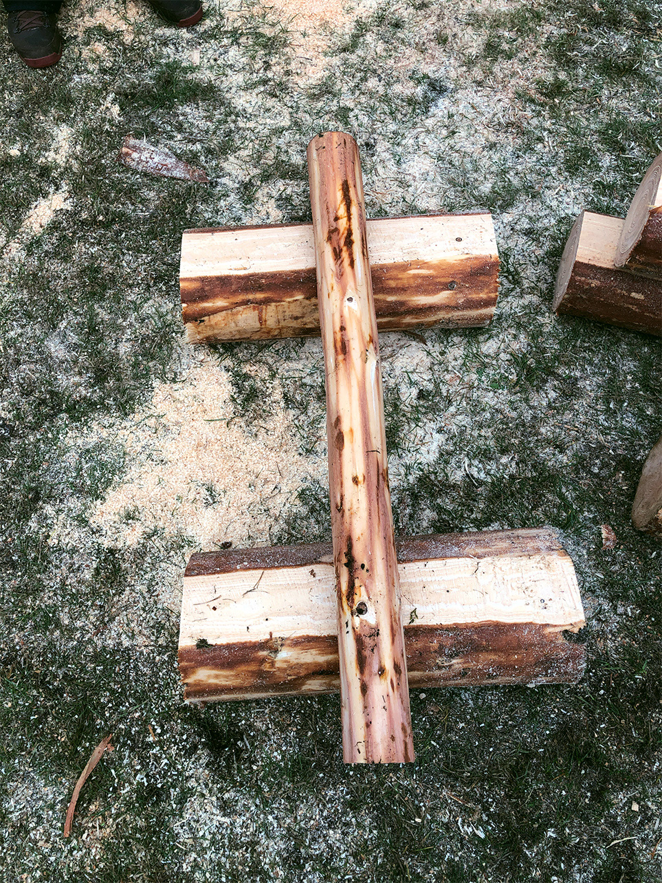 Strut of DIY garden table is placed on top of the two bottom logs