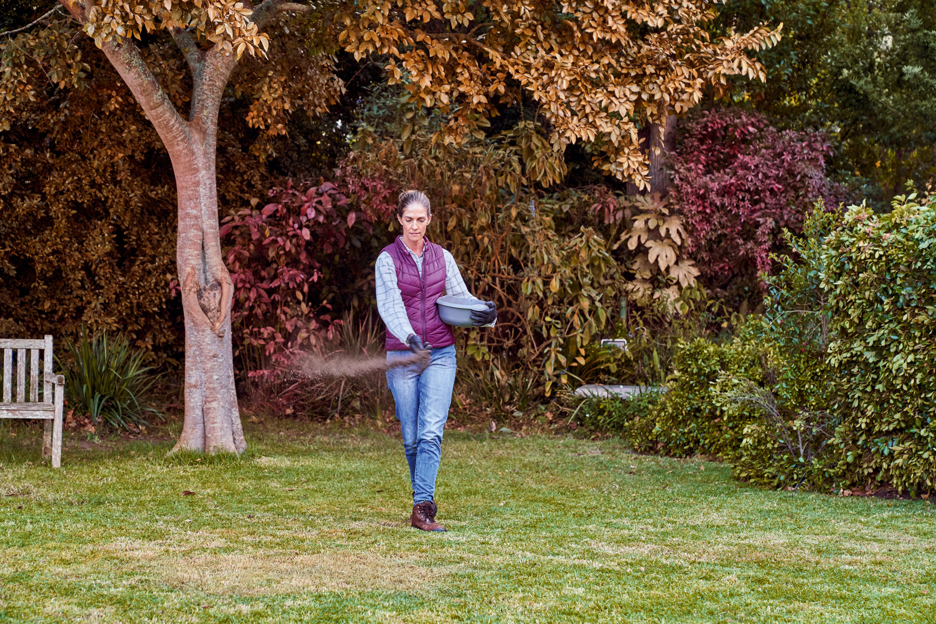 Woman spreads fertiliser in her garden