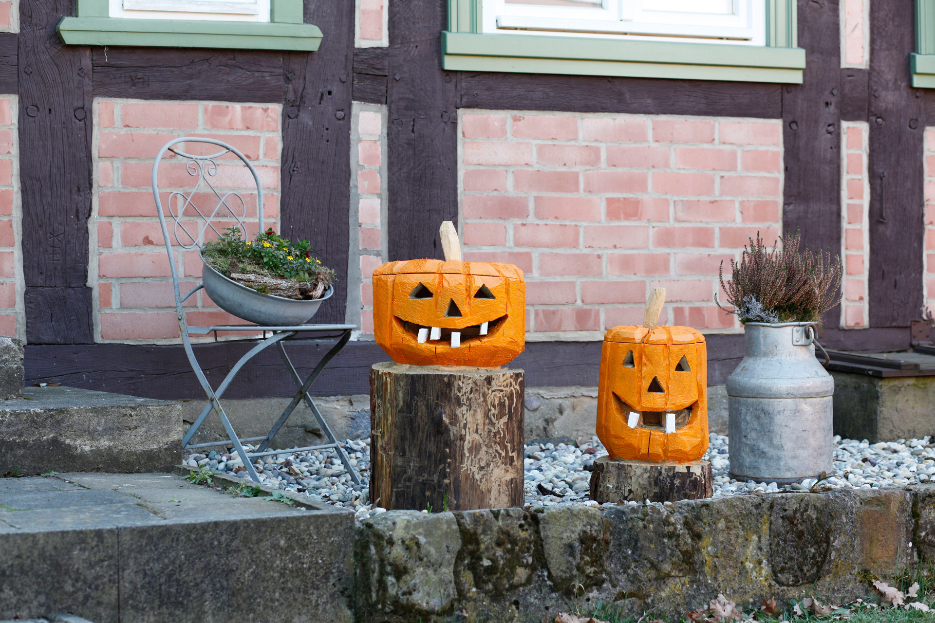 Painted DIY wooden pumpkin decorations made from logs outside a house