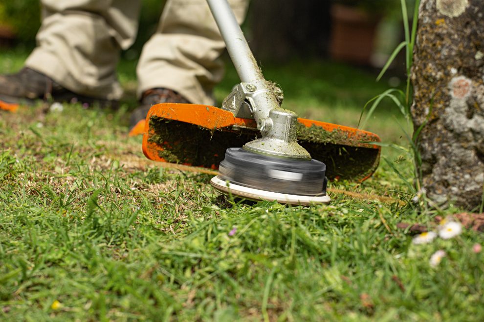 Close-up of STIHL FS 240 trimming close to a tree base