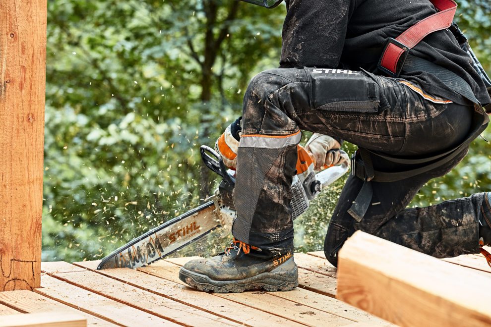 Operator wearing STIHL protective trousers while cutting branches