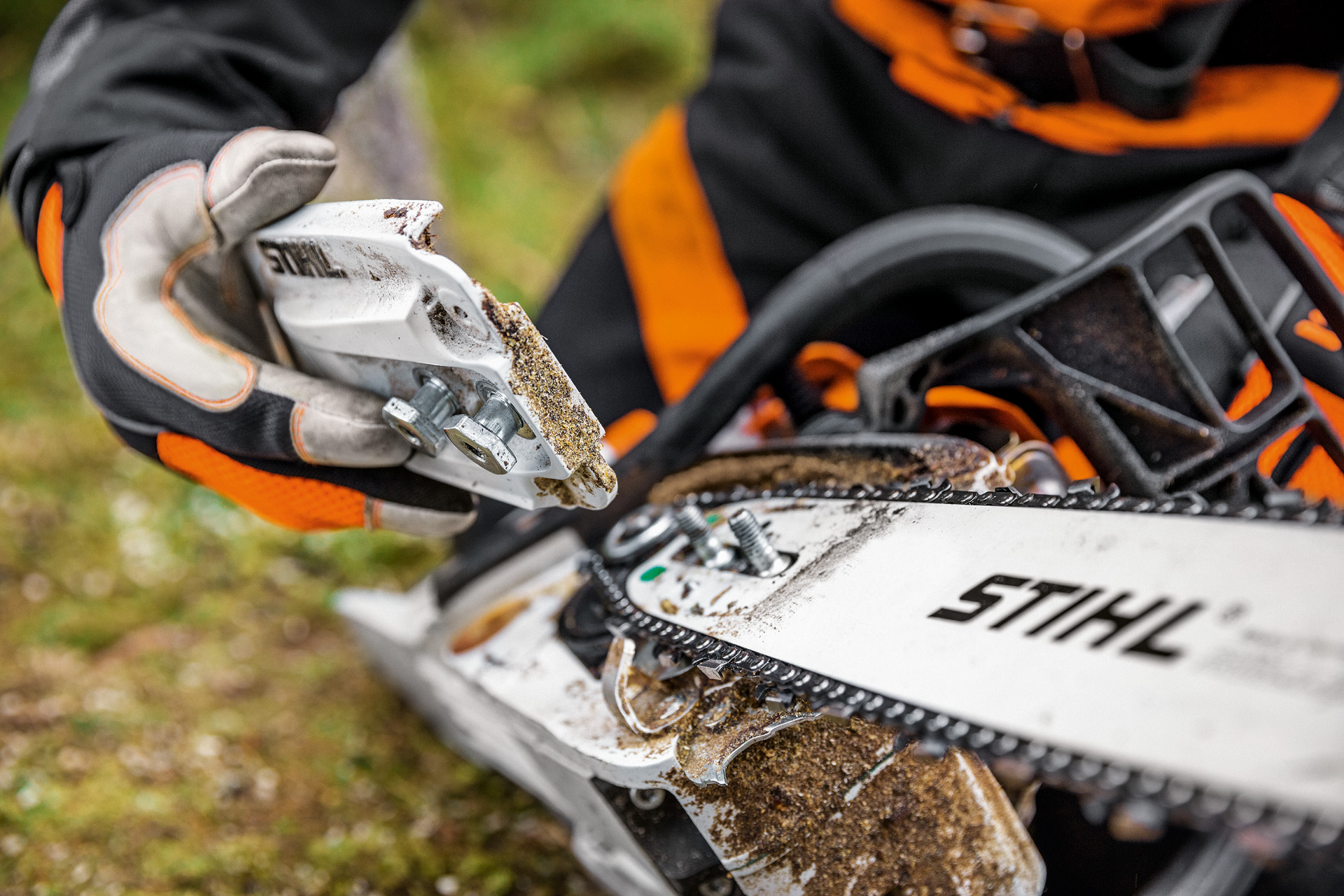 Close-up of the chain sprocket cover being removed from a STIHL MS 261 C-M petrol chainsaw 