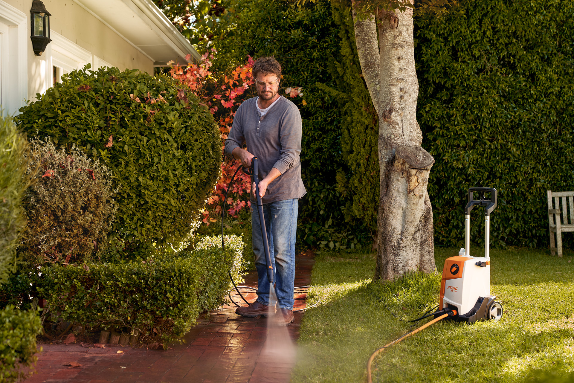 A man cleaning paving in front of his house with a STIHL RE 110 high-pressure cleaner 