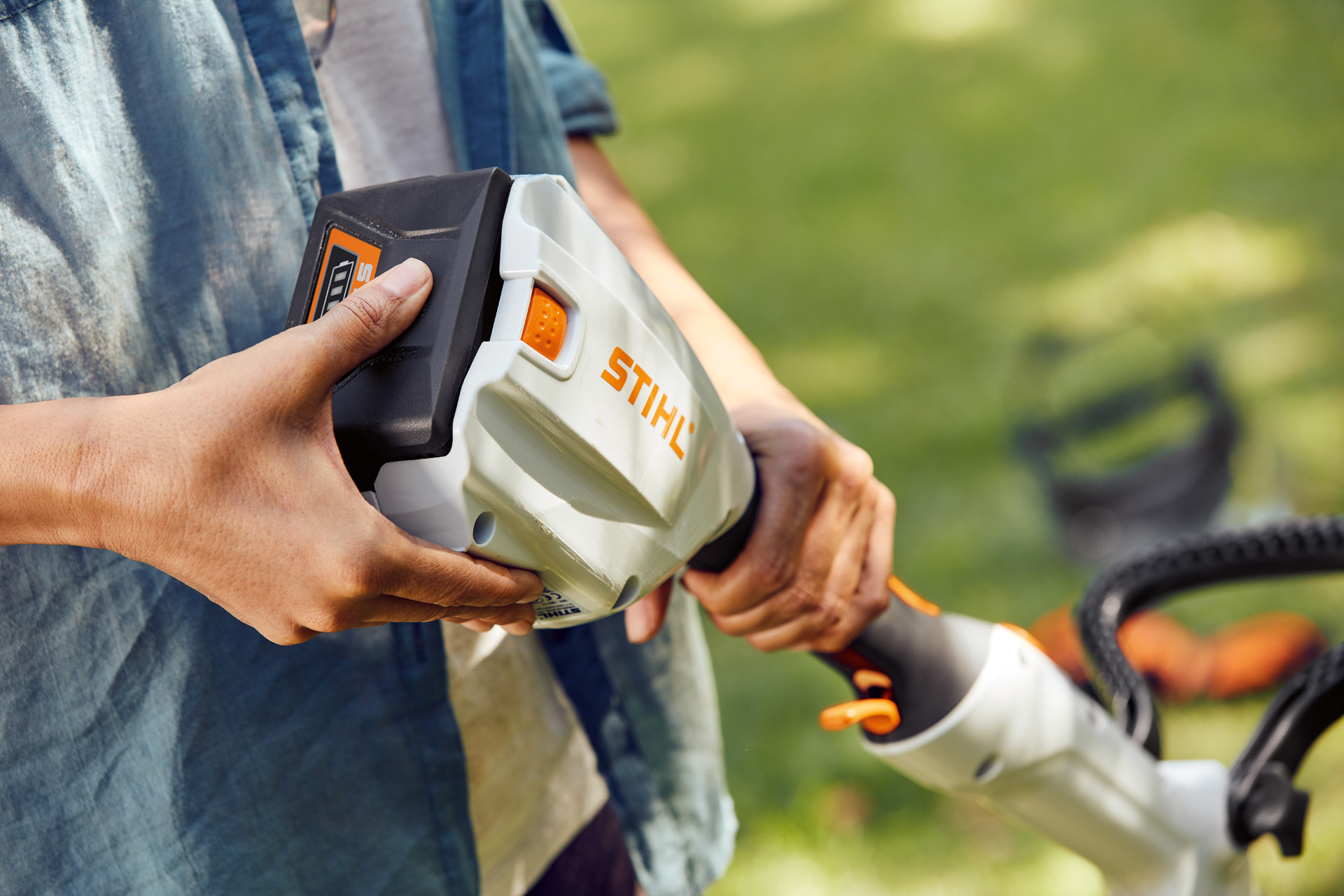 A person holds the STIHL FSA 56 battery-powered brush cutter in his hand and strokes the battery.