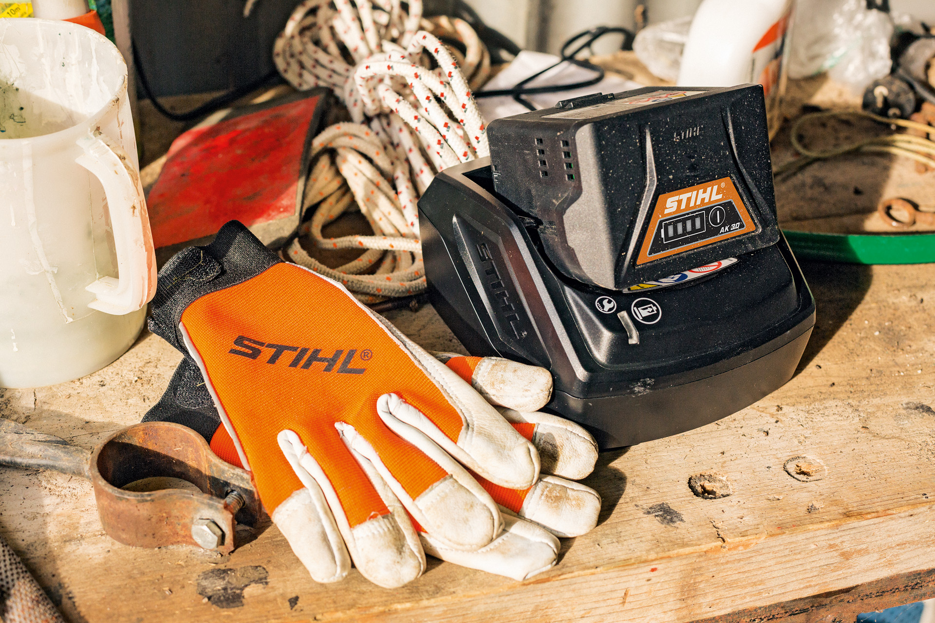 A STIHL AK Series lithium-ion battery being charged alongside gloves