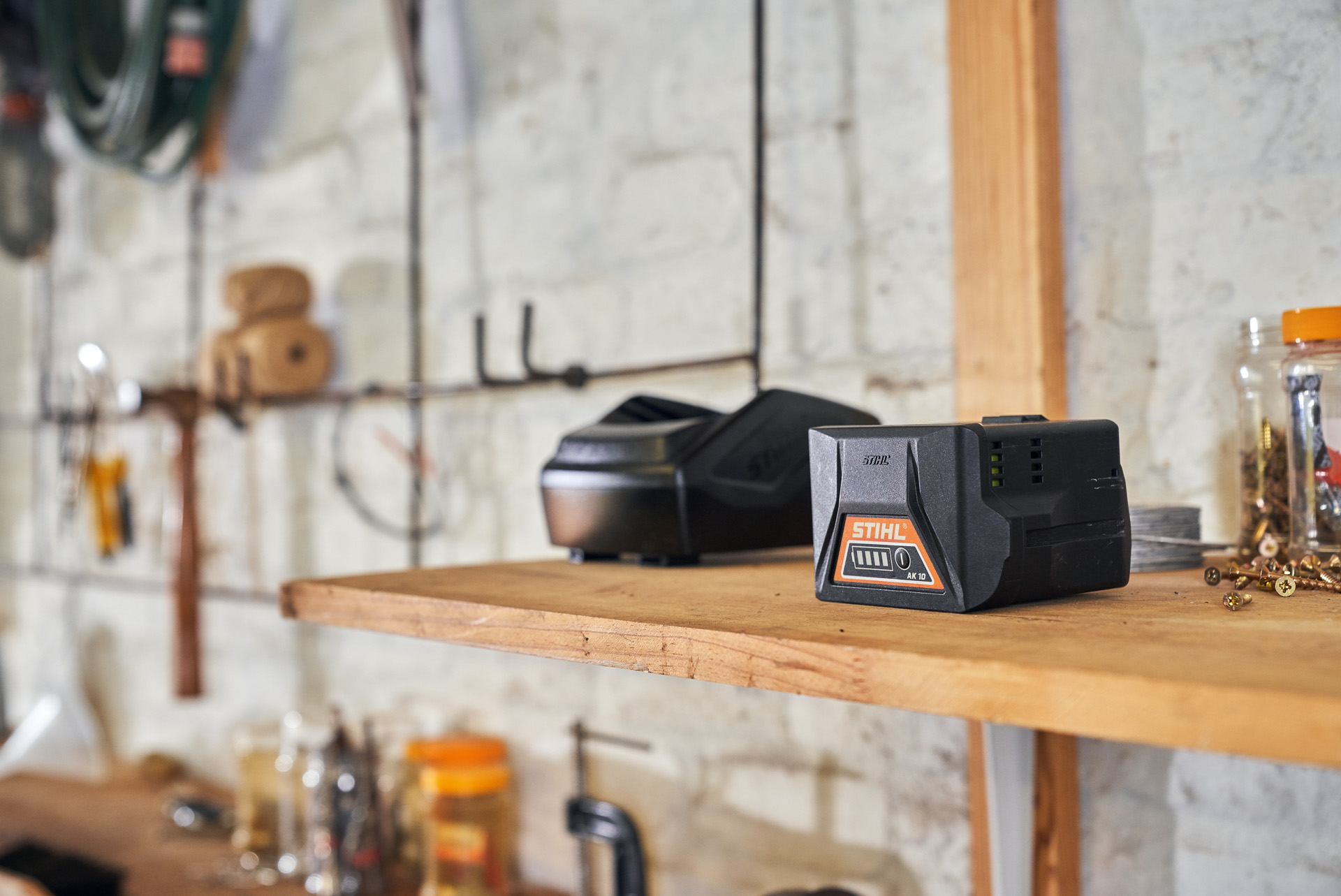 A STIHL battery and charger on a wooden shelf in a workshop