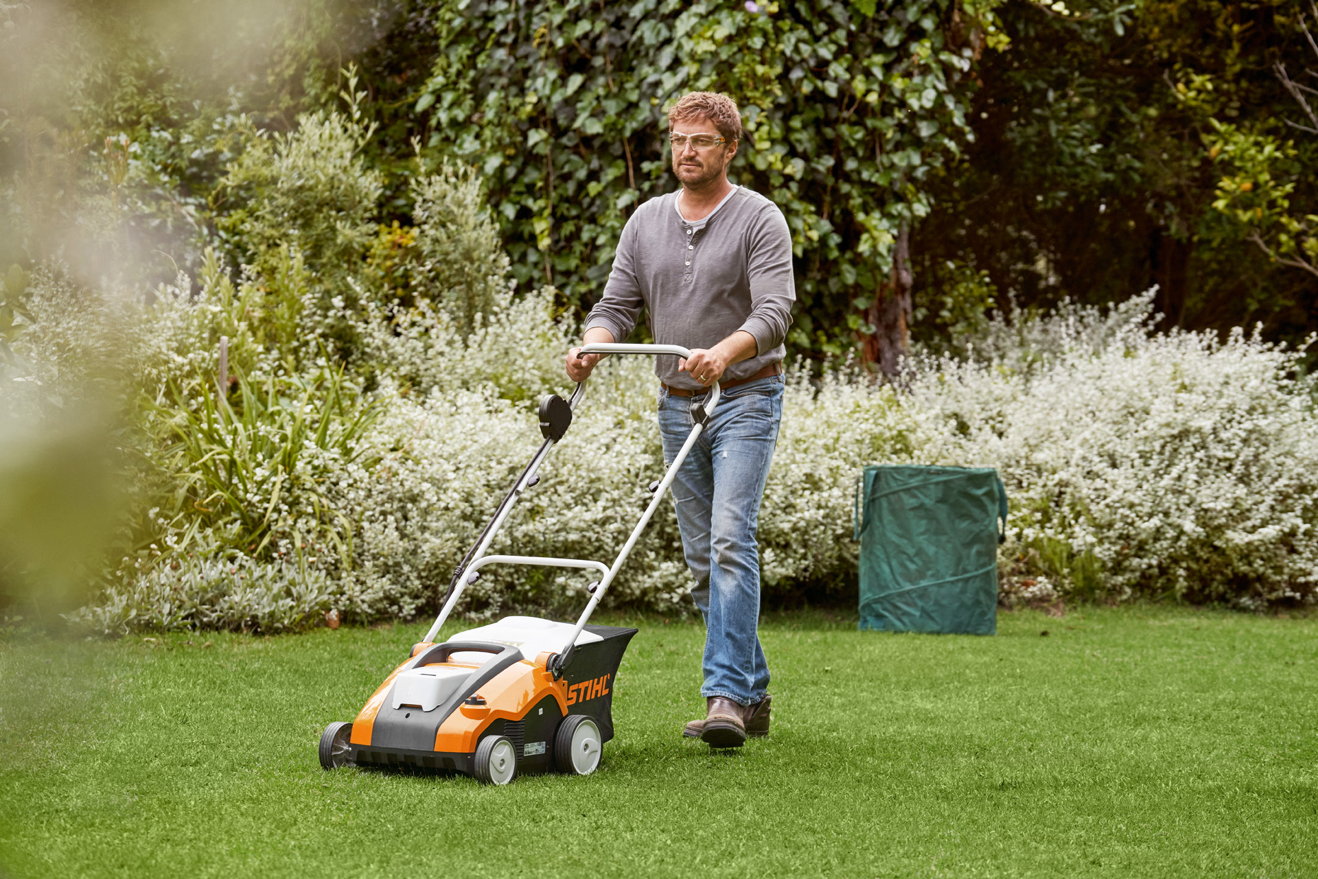 Man scarifies green lawn with a STIHL RLA 240 