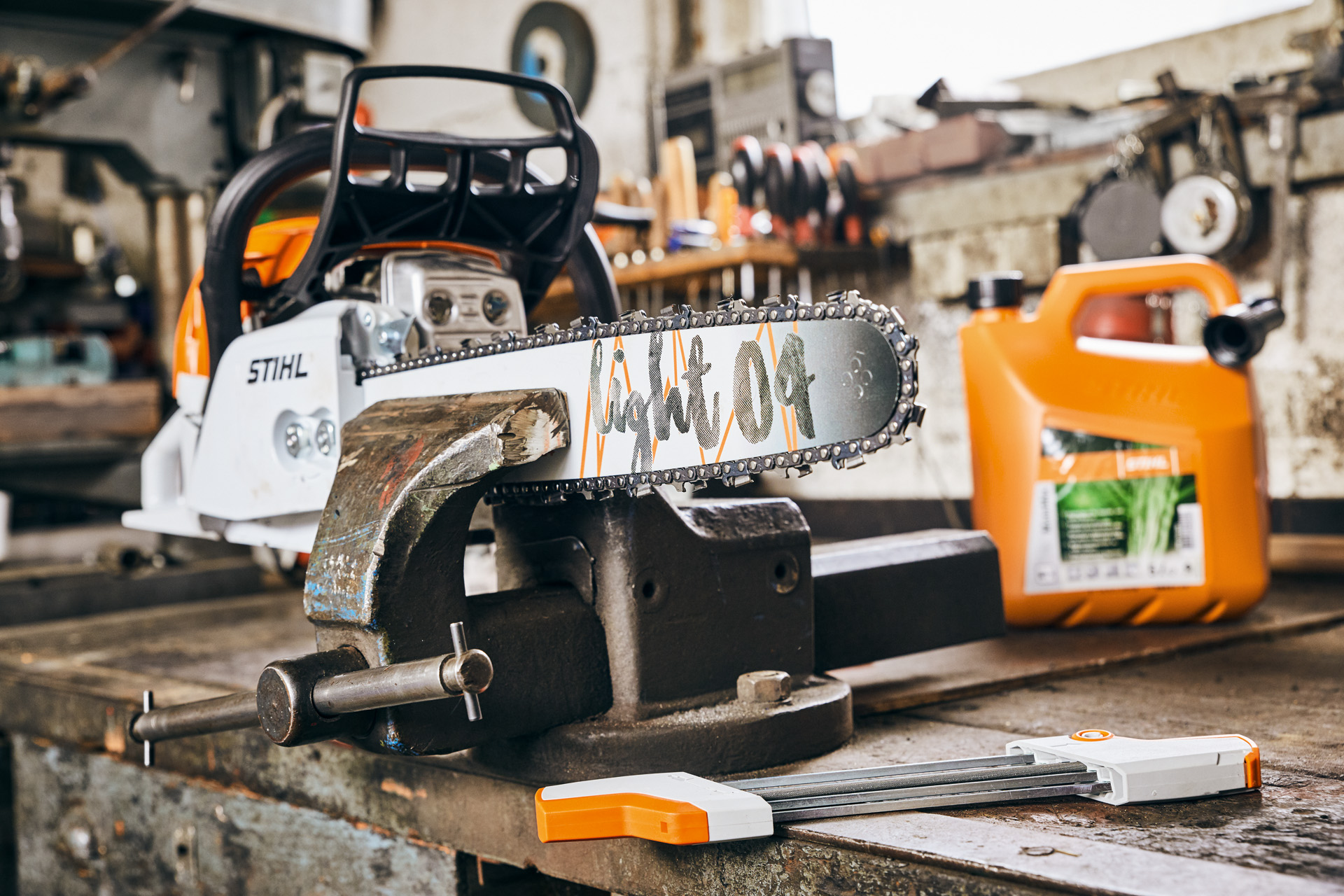 A STIHL MS 261 C-M petrol chainsaw with Light 04 guide bar clamped to a workbench, and bottle of STIHL MotoMix behind it