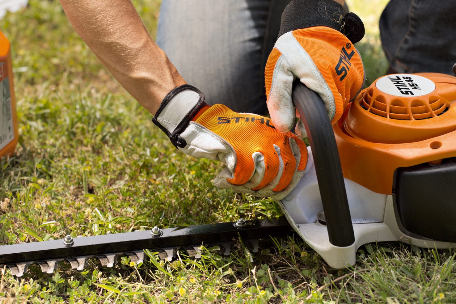 User wearing gloves and glasses cleaning a STIHL hedge trimmer