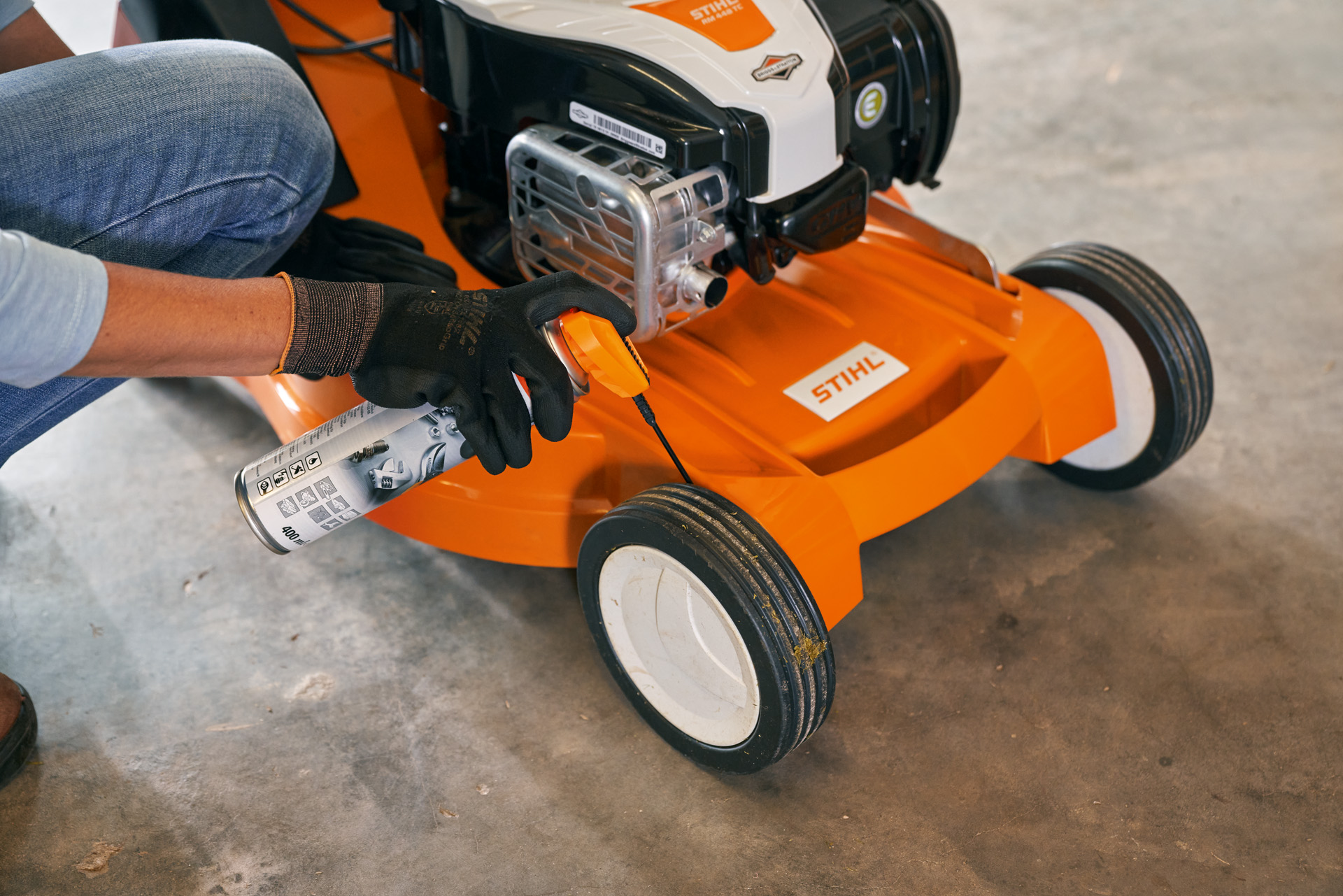 Woman stores her STIHL petrol lawn mower RM 448 TC in a garage 