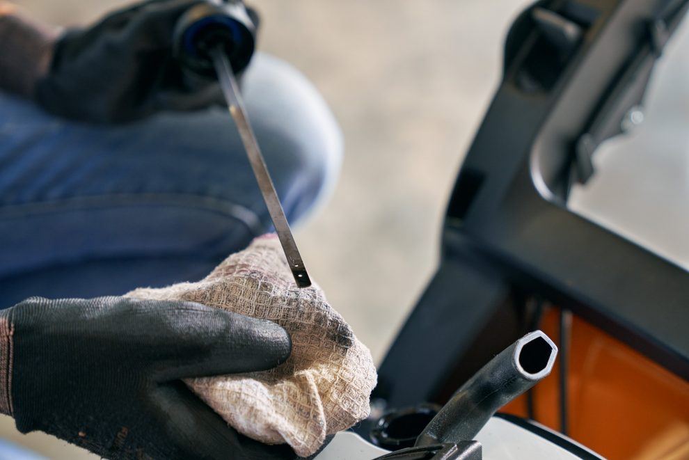 Checking the oil level of a lawn mower using a dipstick