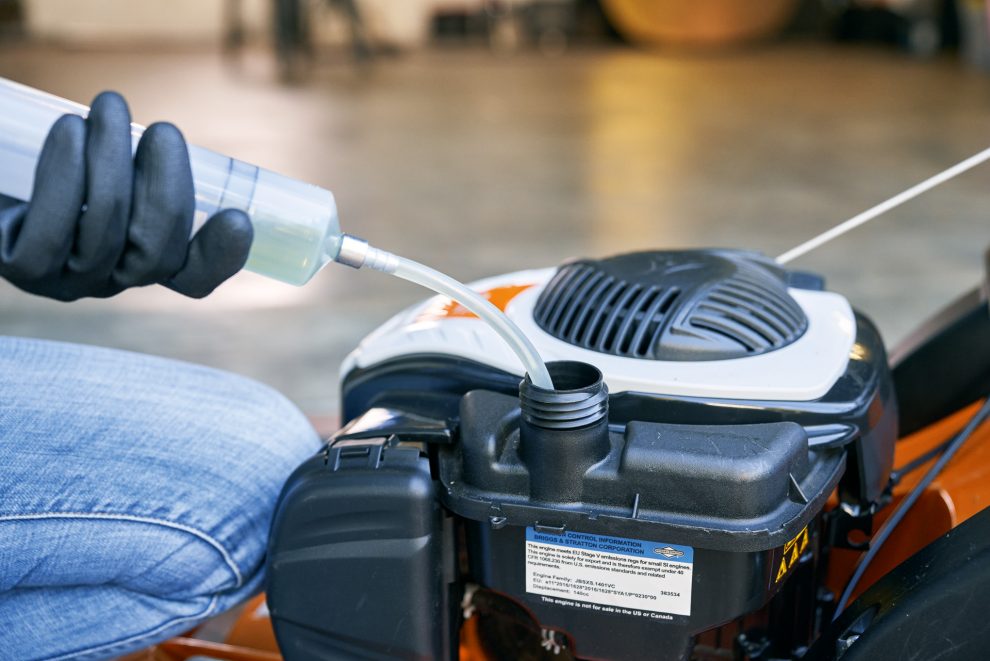 Person draining petrol from a STIHL RM 448 TC lawn mower