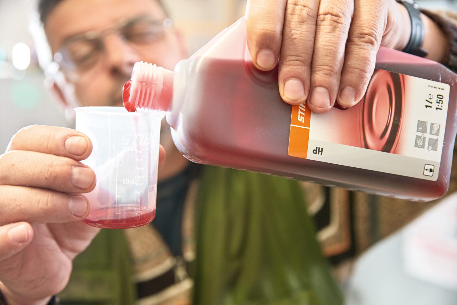 Man pouring STIHL HP 2-stroke engine oil into a measuring beaker