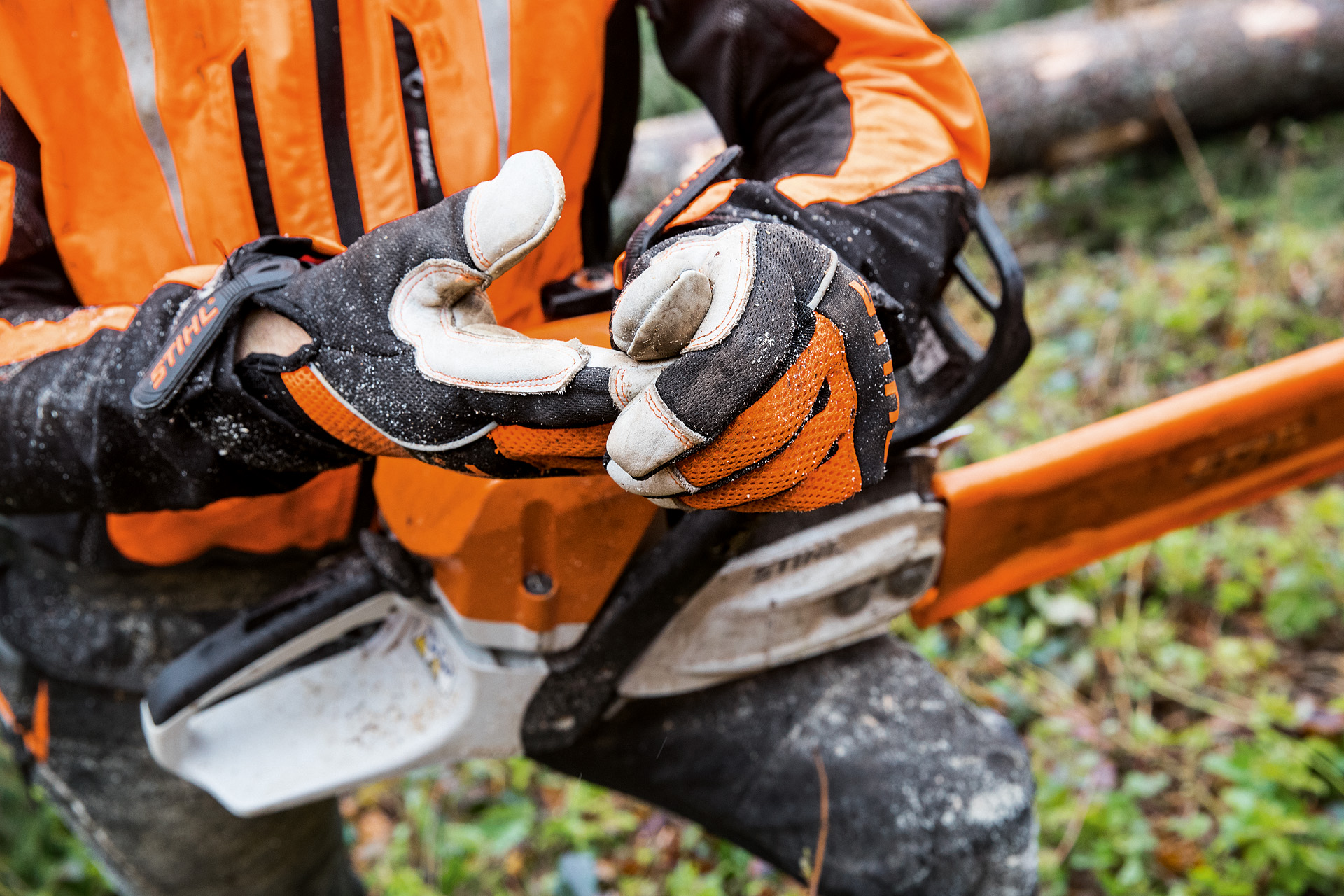 Close-up of STIHL ADVANCE Ergo MS protective gloves for chainsaw work being worn by someone holding a chainsaw