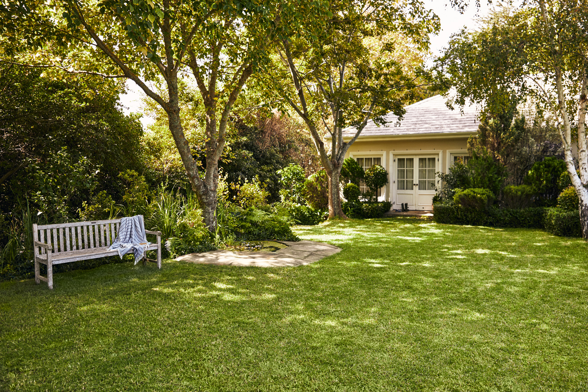 A STIHL iMOW® robot lawn mower on a neat green lawn bordered by plants and shrubs