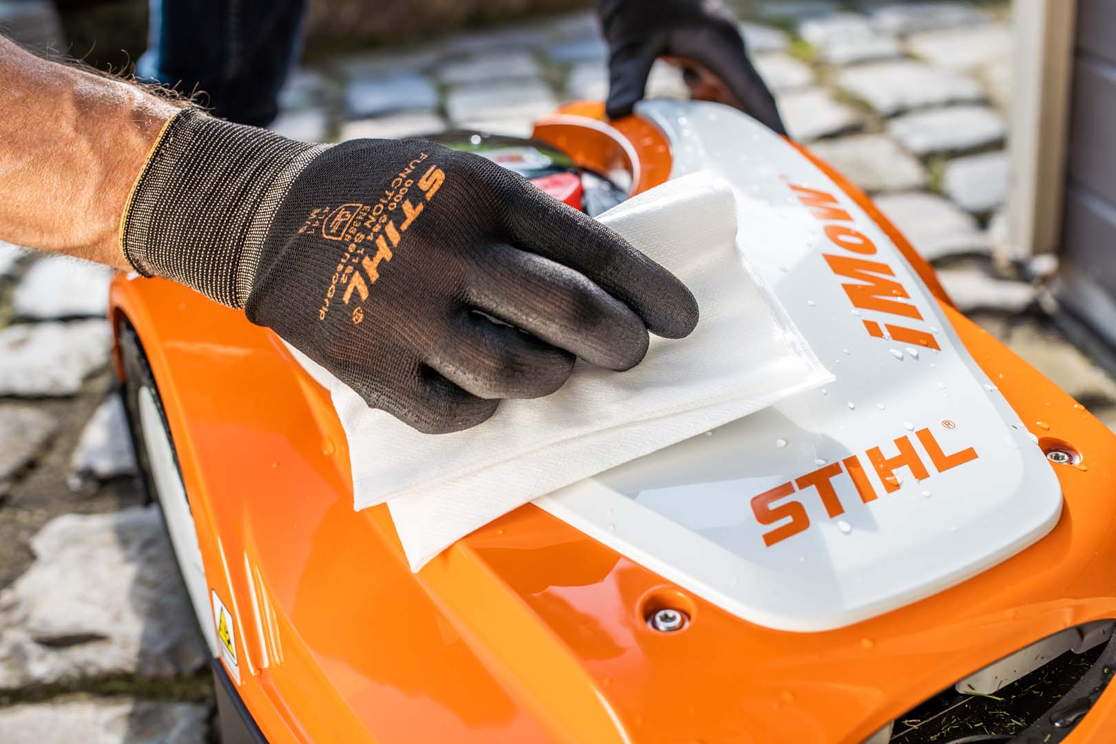 Close-up of a STIHL iMOW® 422 robot lawn mower being cleaned with a cloth