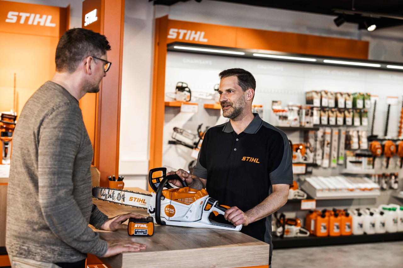STIHL dealer advises customers on the STIHL MSA 300 cordless chainsaw in his showroom