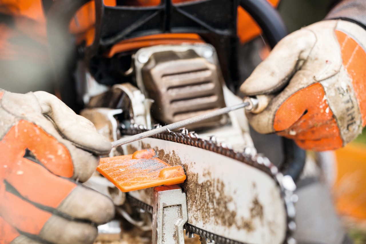 Close-up of sharpening a saw chain with a round file 