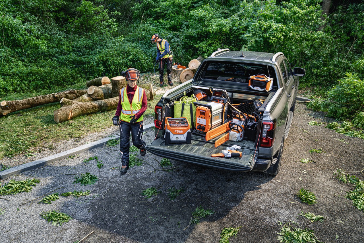Woman walking to flatbed truck on a forest access road wiht STIHL battery-powered tools in the back